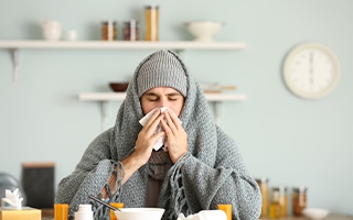 Mann mit Erkältung putzt sich die Nase
